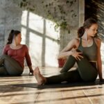 two ladies sitting on yoga mats doing exercises