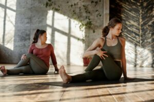 two ladies sitting on yoga mats doing exercises
